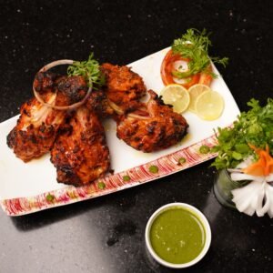 Deliciously grilled chicken with mint chutney, herbs, and lemon slices. Perfect dinner dish.